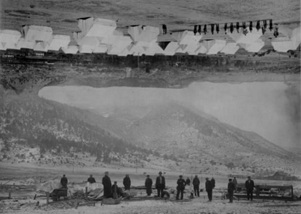 A surreal black and white collage made up of archived images. The picture shows several men in old-fashioned attire with a mountainous and desolate looking area in the background. The top of the image is upside-down and shows several men (also in old-fashioned attire) lined up. Lots of white tents can be seen nearby.