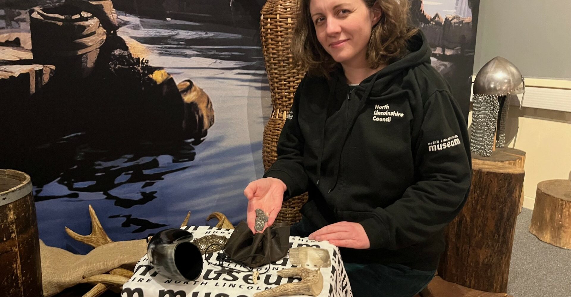 member of the museum team, wearing a black hoodie showing a handful of items to the camera