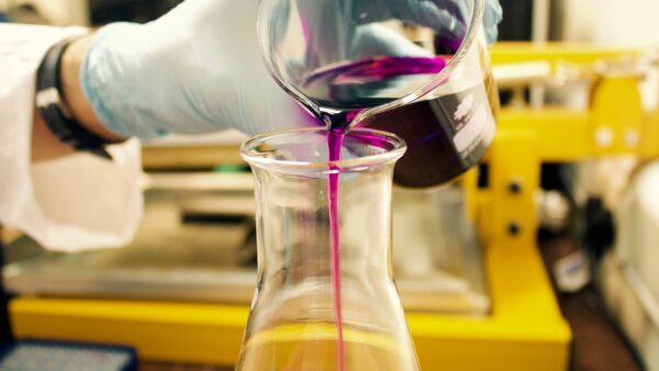 a hand pouring purple liquid into a glass jar