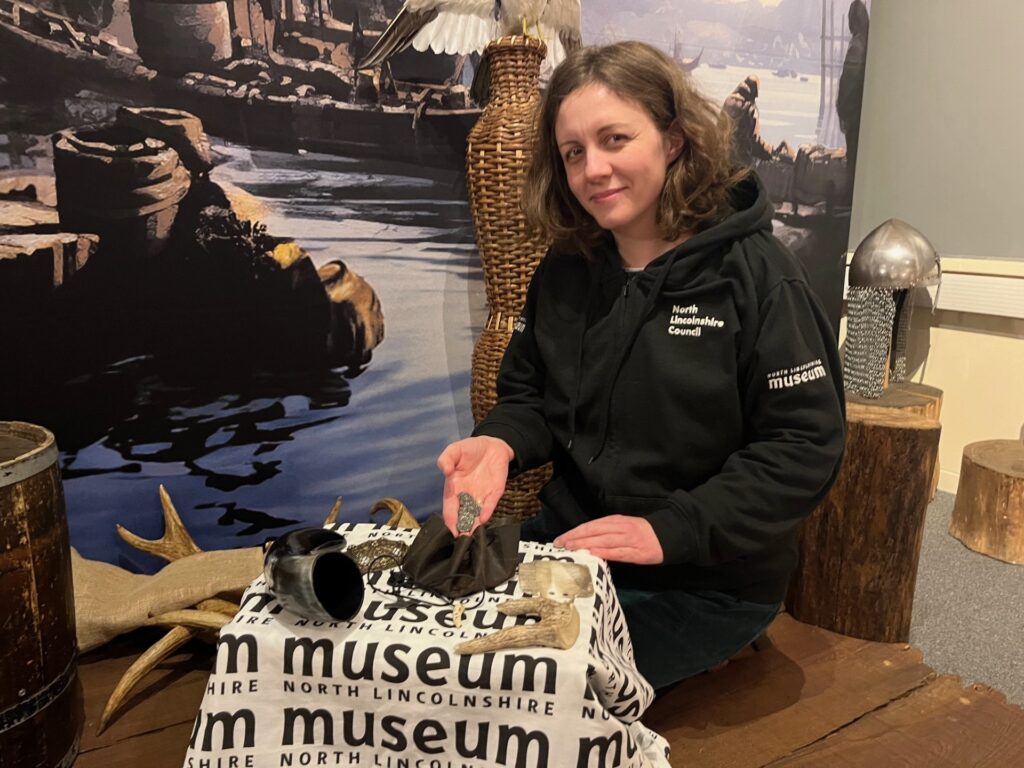 member of the museum team, wearing a black hoodie showing a handful of items to the camera