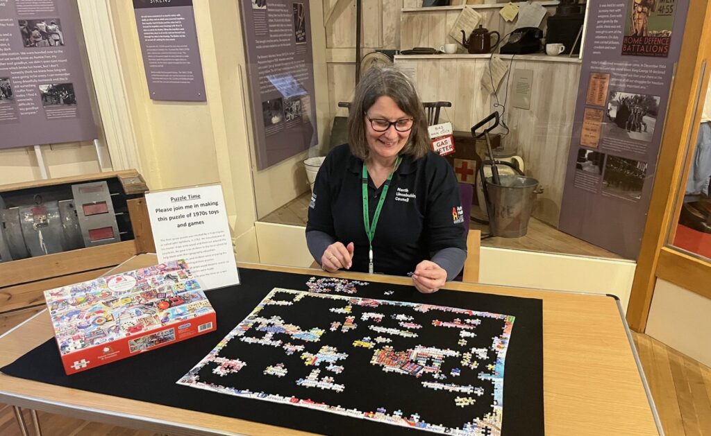 a member of the learning team with a board game with a stand of artefacts