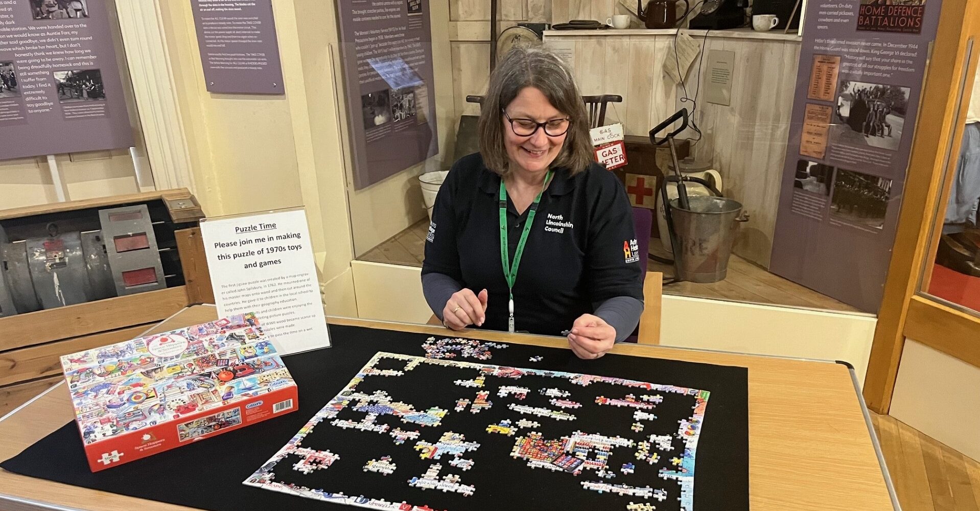 a member of the learning team with a board game with a stand of artefacts