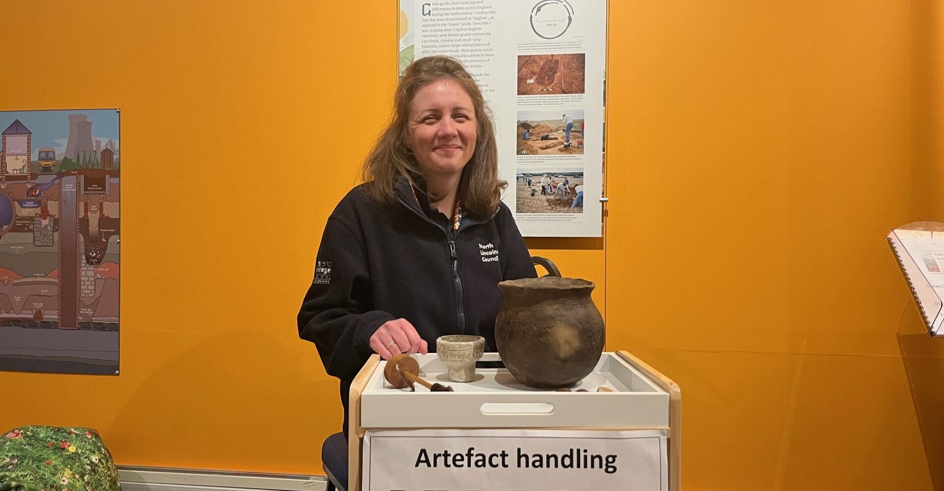 a member of the learning team with a stand of artefacts