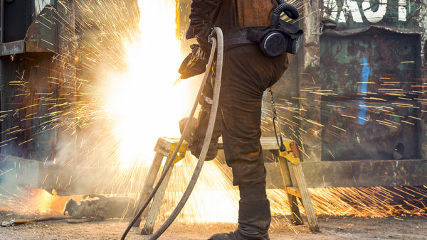 a man wwelding with sparks coming out of a long object with a hose