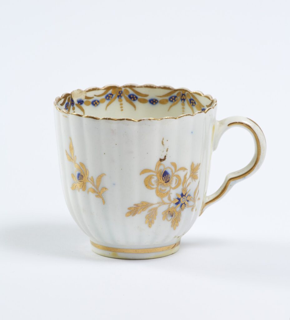A white porcelain tac cup decorated with yellow flowers.