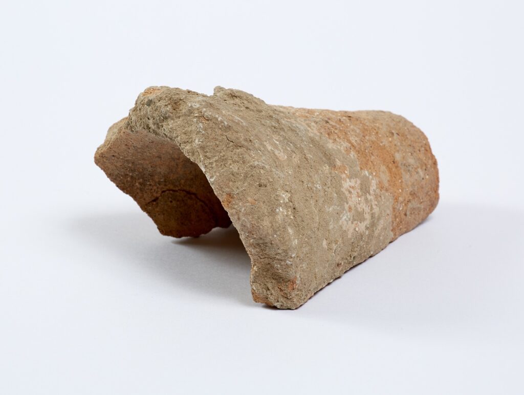 Orange coloured pointed base from a pottery vessel.