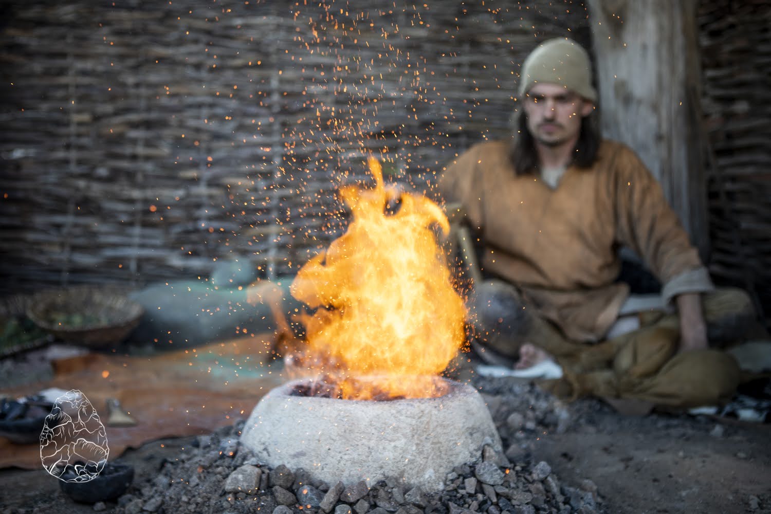 man in themed Viking dress sitting near a fire