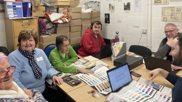 A group of poeple sit around a table. On the table are documents and laptops.